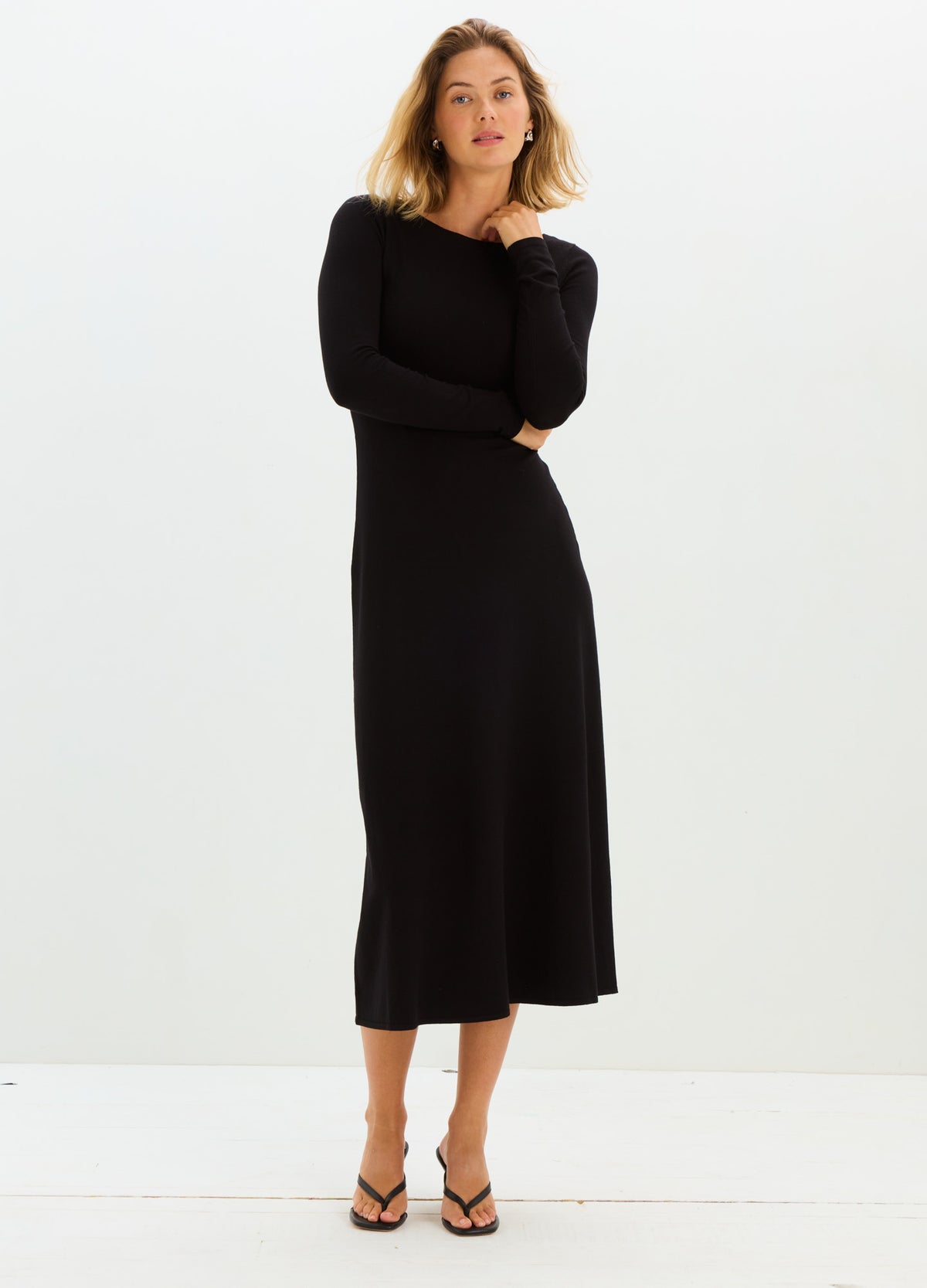 Black long-sleeve maternity knit dress with a fitted bodice and flowing skirt reaching mid-calf.