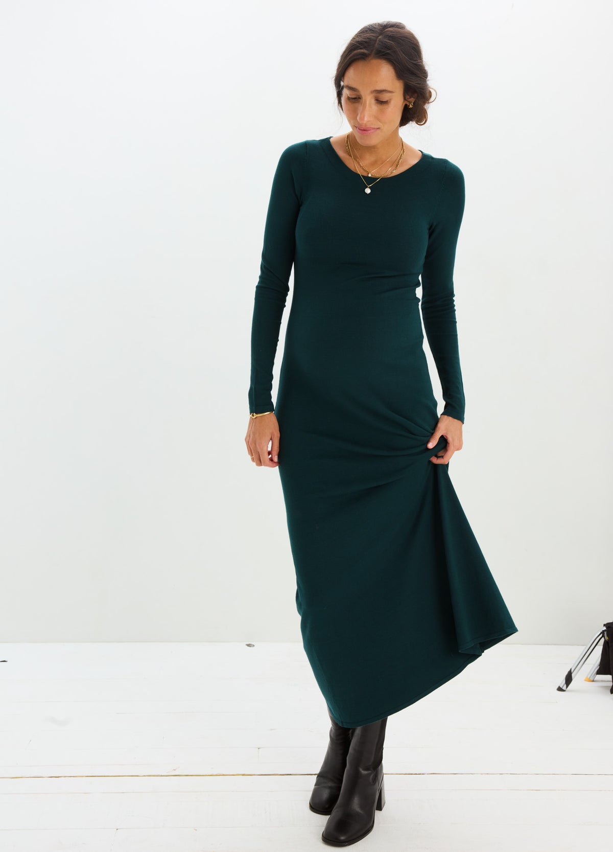 Dark green long-sleeve knit maternity dress with fitted bodice and flowing skirt paired with black ankle boots.