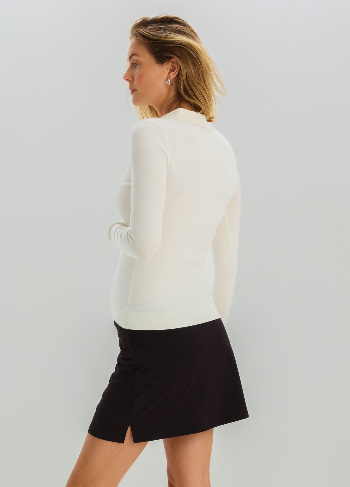 Cream knit long-sleeve maternity nursing polo paired with a black A-line skirt.