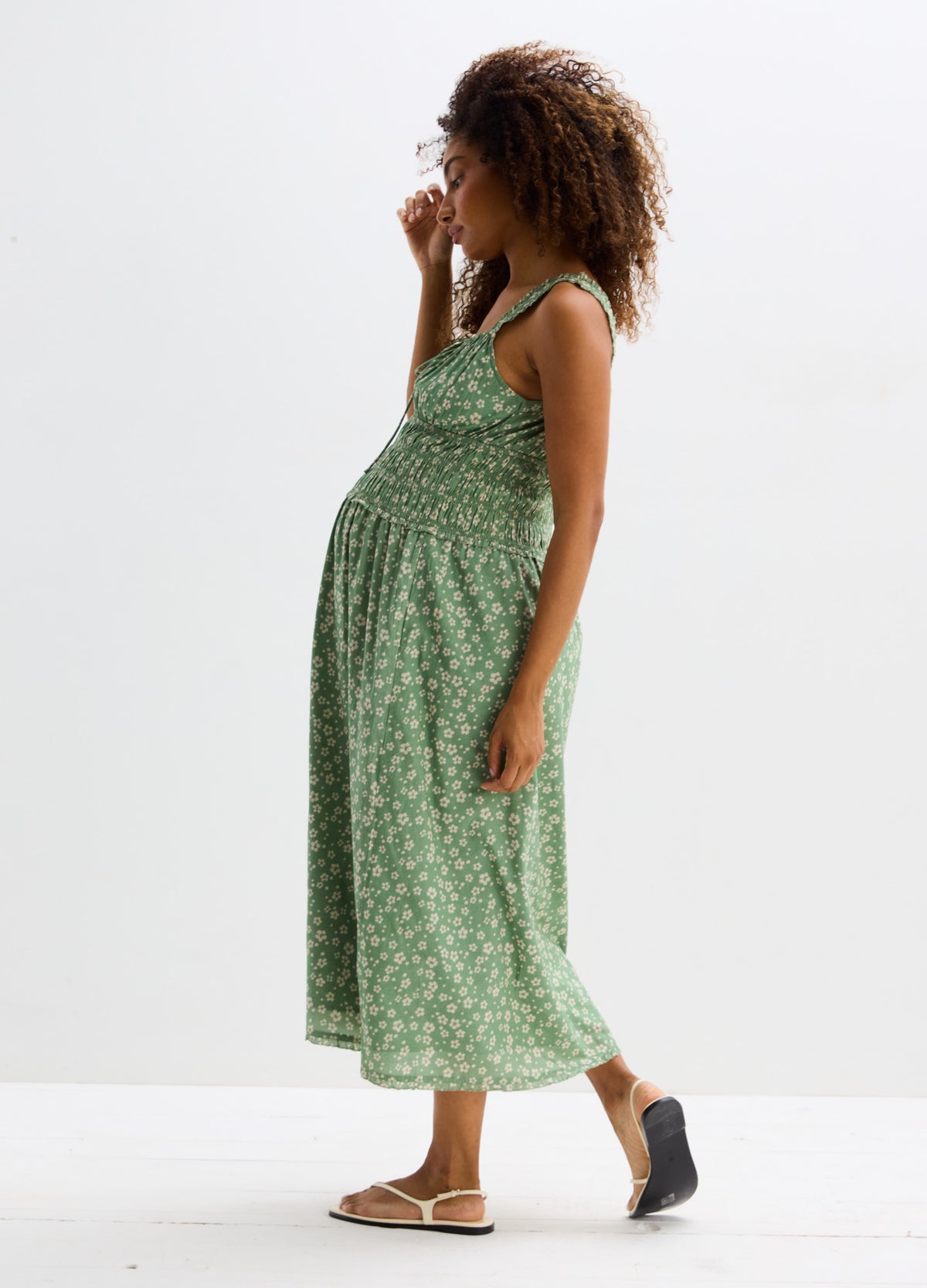 Light green maternity dress with white floral print, sleeveless with a fitted empire waist and flowy skirt.