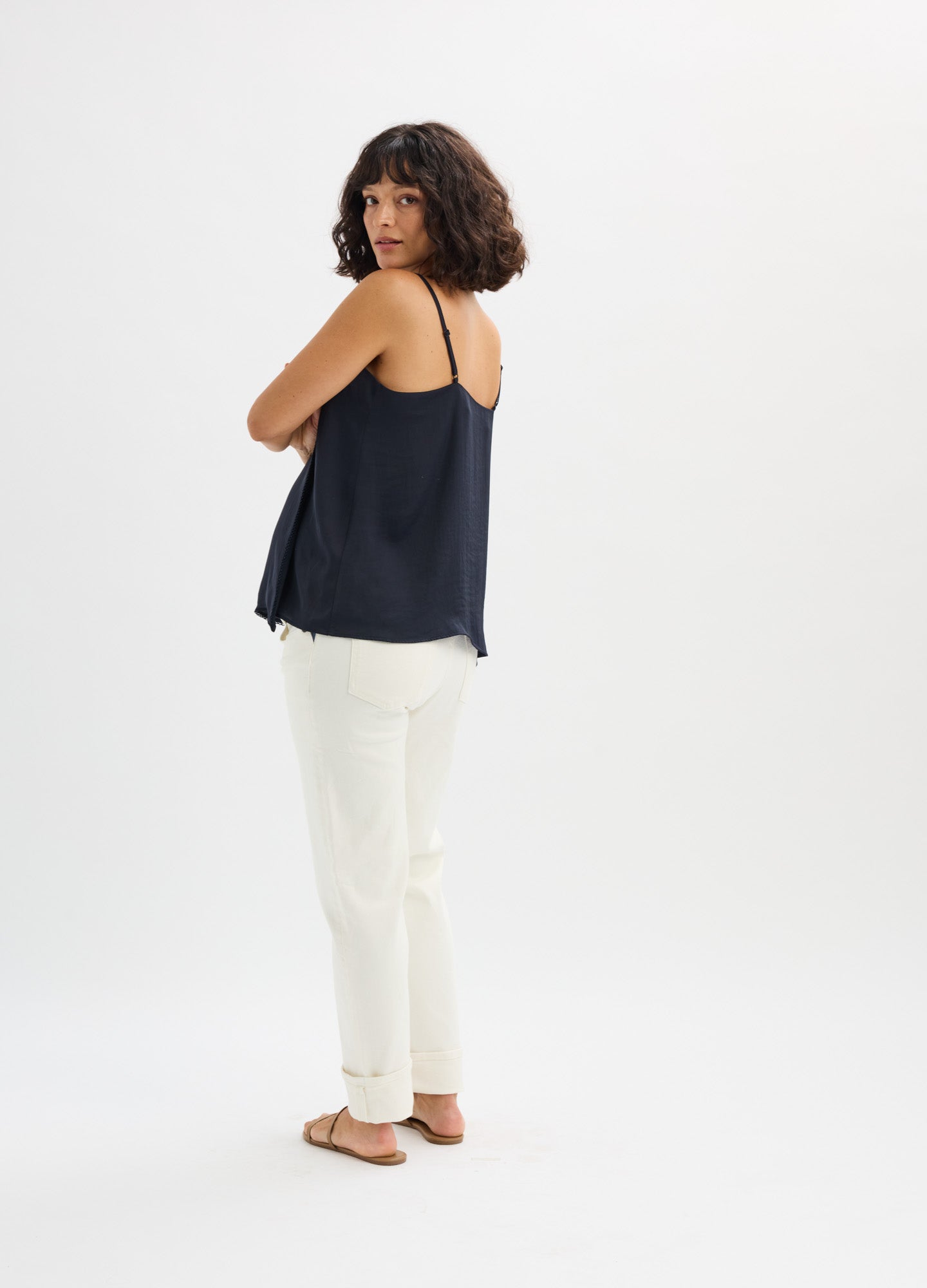 Black satin maternity camisole with thin adjustable straps, loose fit, paired with white pants.