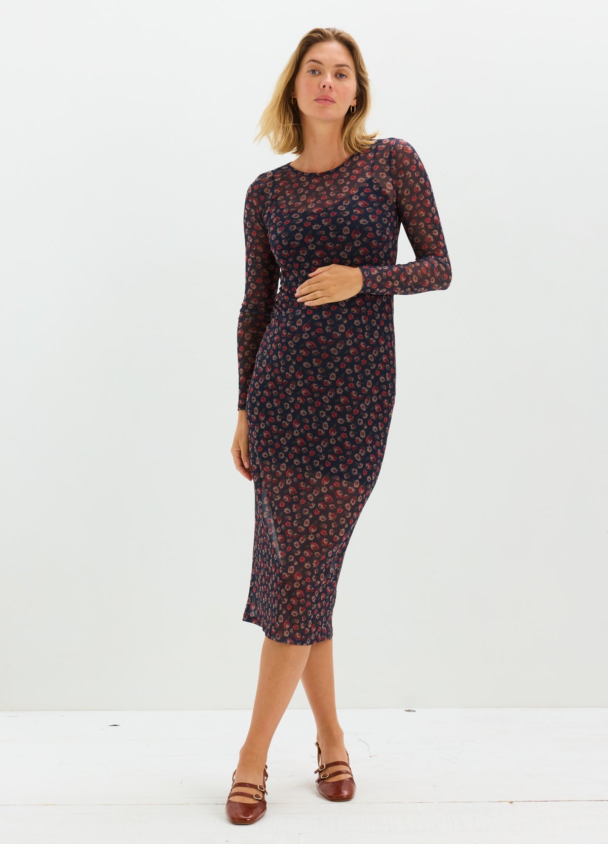 Midi-length fitted maternity dress with long sleeves, dark base color, and small red floral print.