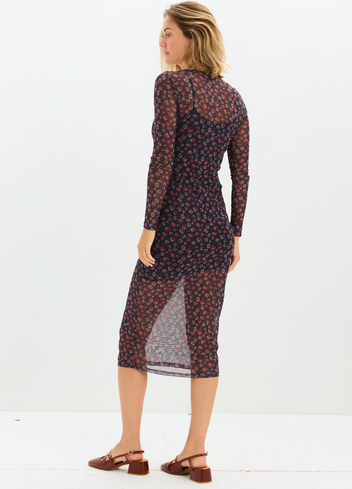 Navy blue maternity dress with red floral pattern, long sleeves, sheer midi skirt, fitted silhouette.