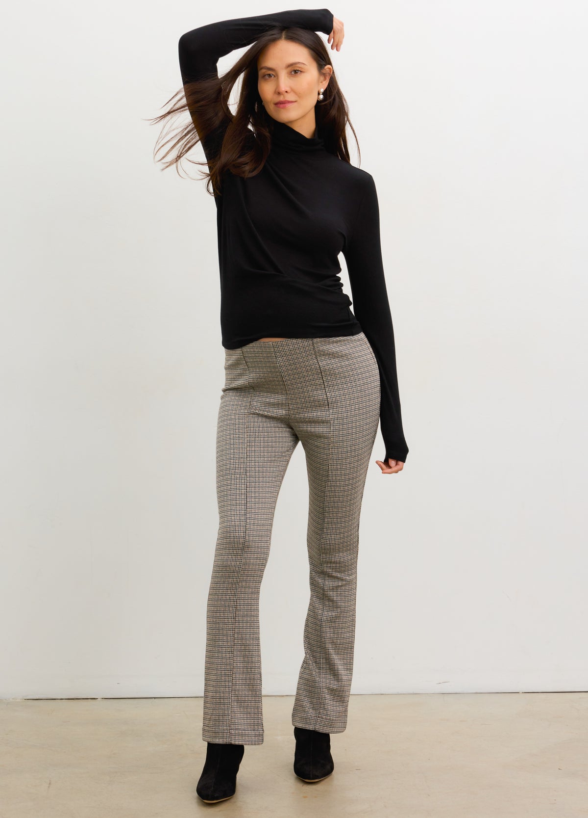 Pregnant woman wearing mini houndstooth maternity seamed stretch crop pants with black turtleneck and boots.