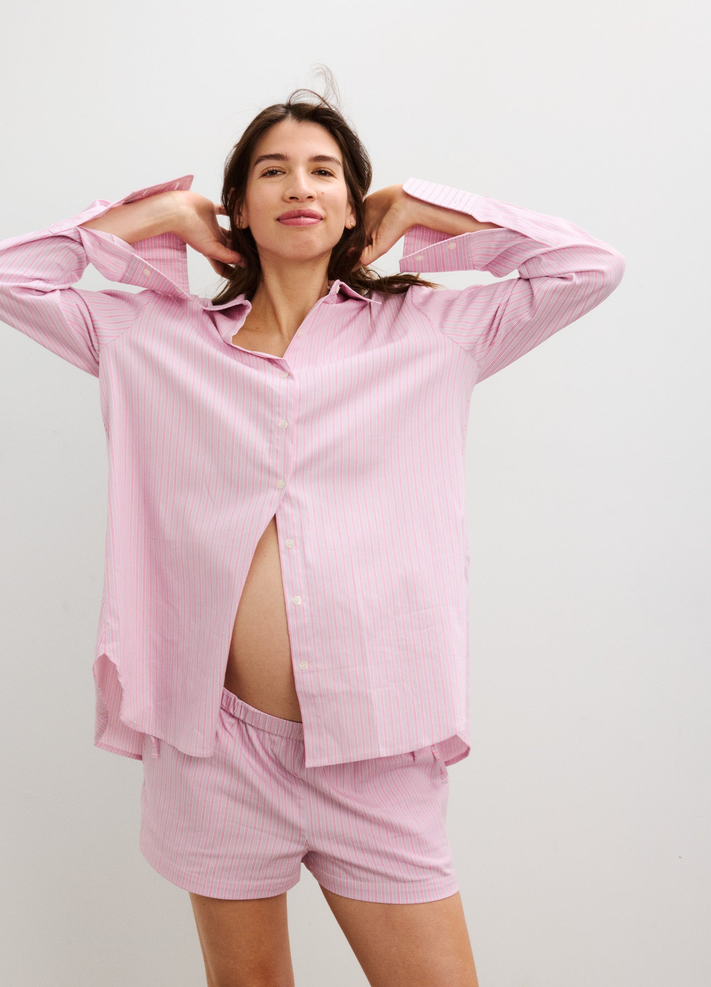 Light pink soft fabric maternity shorts with side tie detail, worn by pregnant model paired with matching button-up shirt.