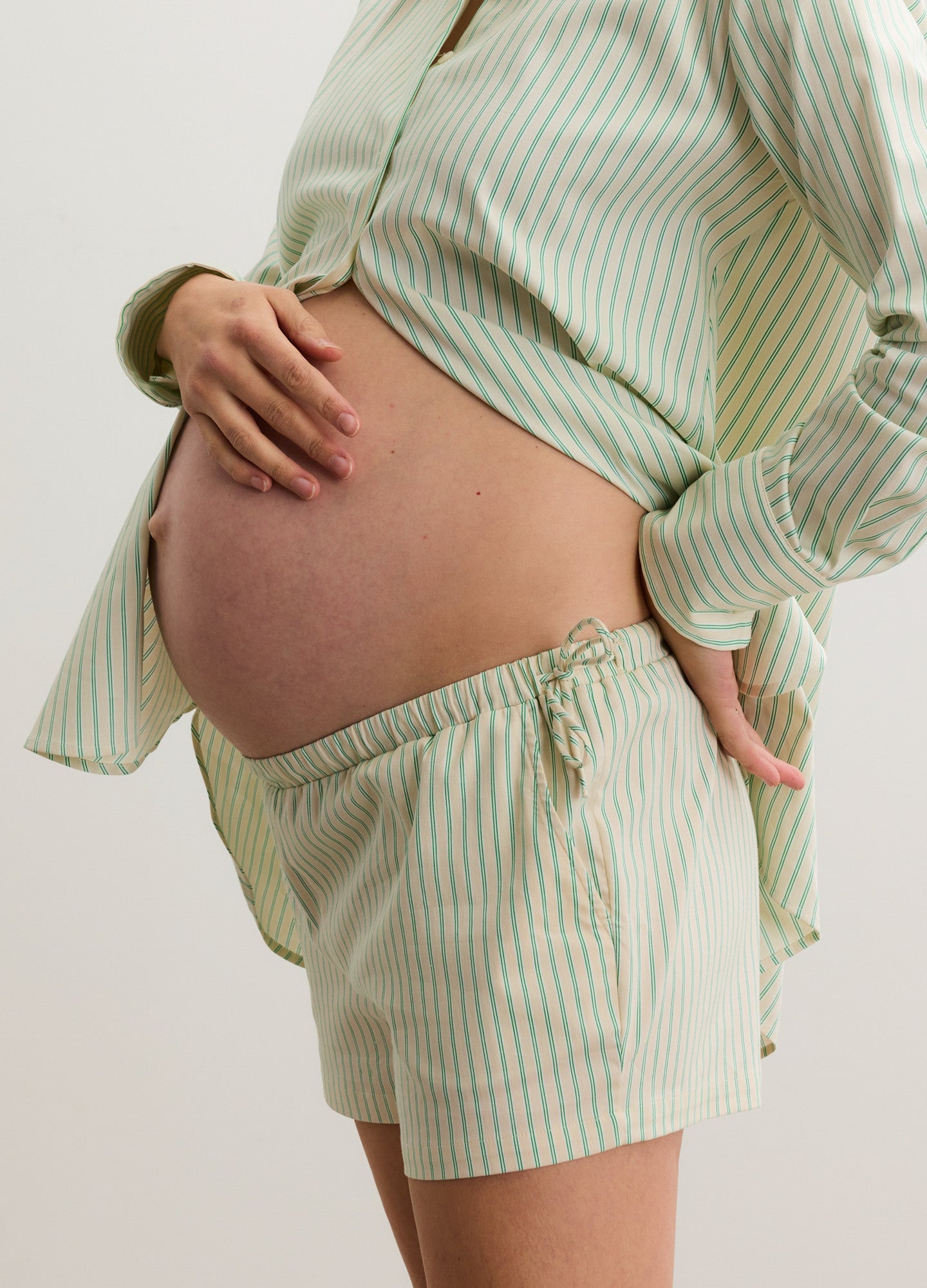 Light green and white striped maternity shorts with adjustable side ties, designed for pregnant comfort.