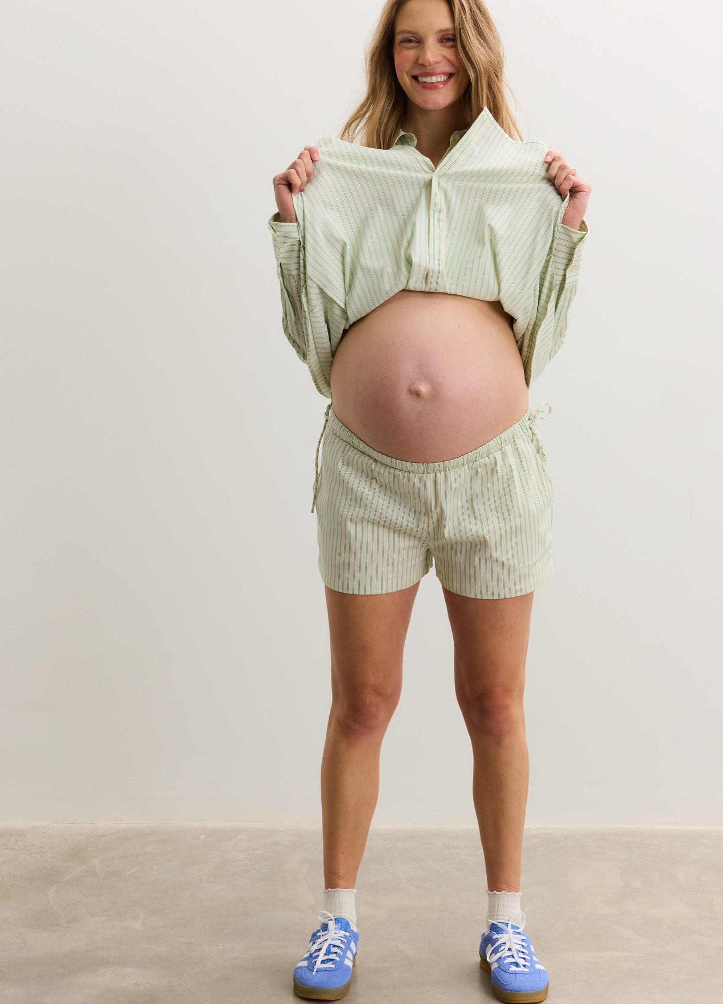 Light green maternity shorts with adjustable side ties, made of soft, lightweight fabric.