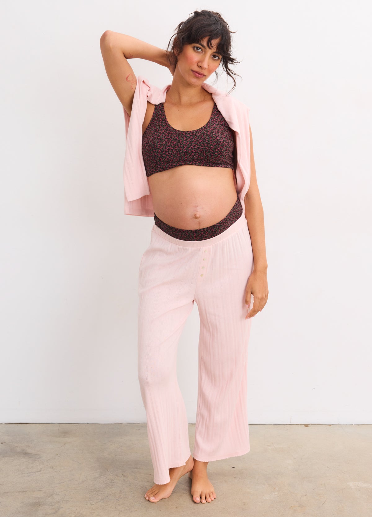 Pregnant woman wearing demi fleur bordeaux maternity bra with soft cups and supportive band, paired with light pink loose.