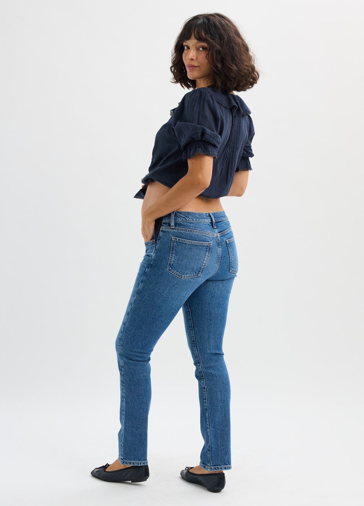 Dark wash slim maternity jeans with full elastic panel, fitted through hips and legs, styled with black flats and navy.