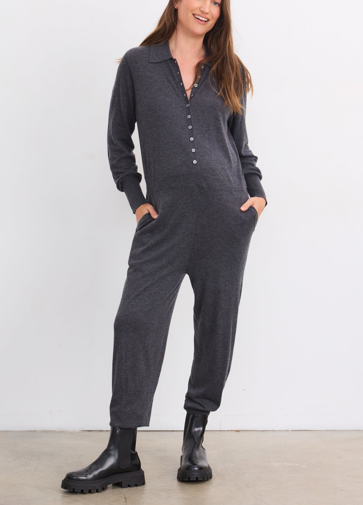 Dark grey soft knit maternity jumpsuit with long sleeves, button-front, tapered legs, and side pockets.