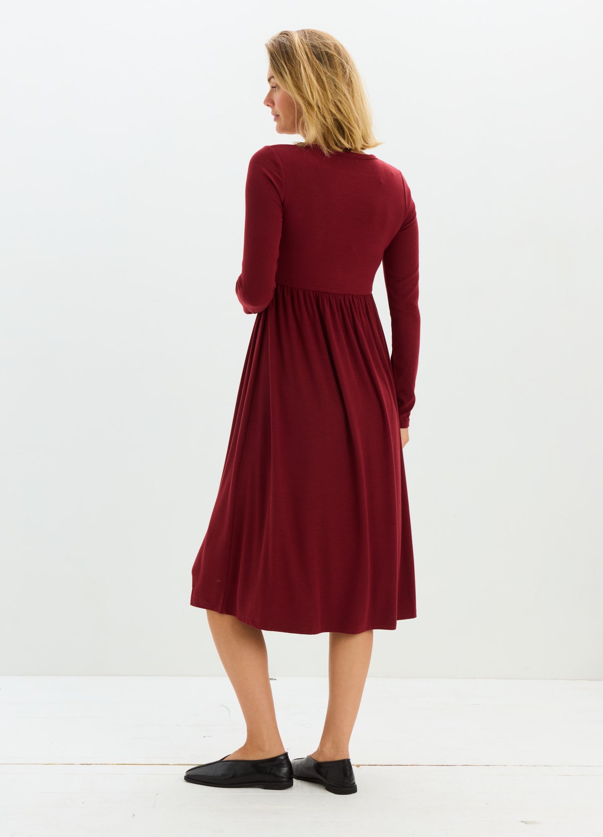 Burgundy ribbed knit maternity nursing dress with long sleeves and gathered waist, midi length.