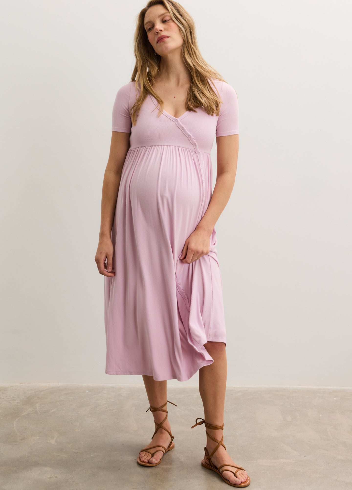 Light pink ribbed knit maternity maxi dress with short sleeves and side seams, styled with brown strappy sandals.