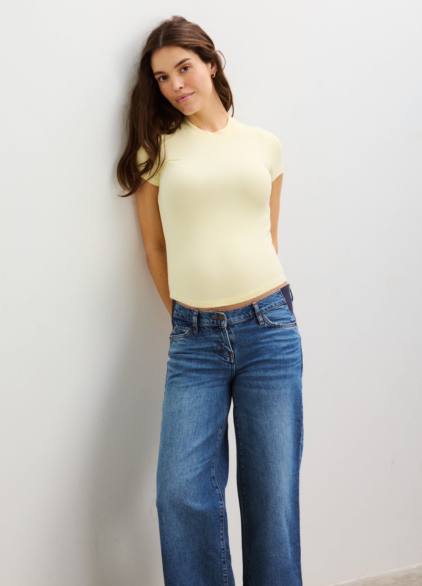 Light yellow ribbed maternity tee with short sleeves and a fitted silhouette, styled with relaxed blue jeans.