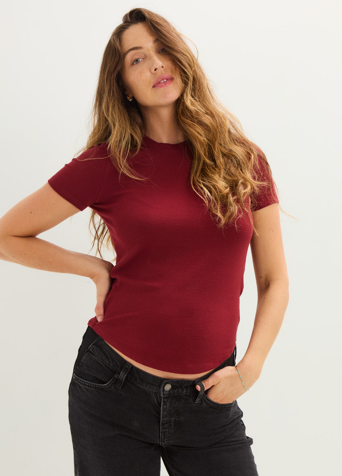 Fitted burgundy ribbed maternity tee with short sleeves and crew neckline on pregnant model.