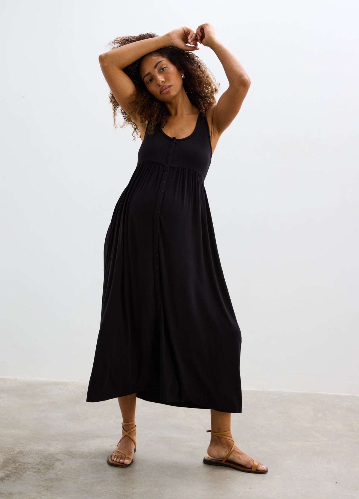 Black soft ribbed nursing tank dress with scoop neck and flowing midi skirt, styled for maternity wear.