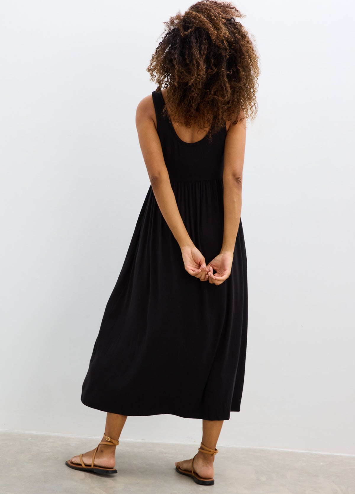 Black sleeveless ribbed nursing tank dress with a midi length and relaxed fit.