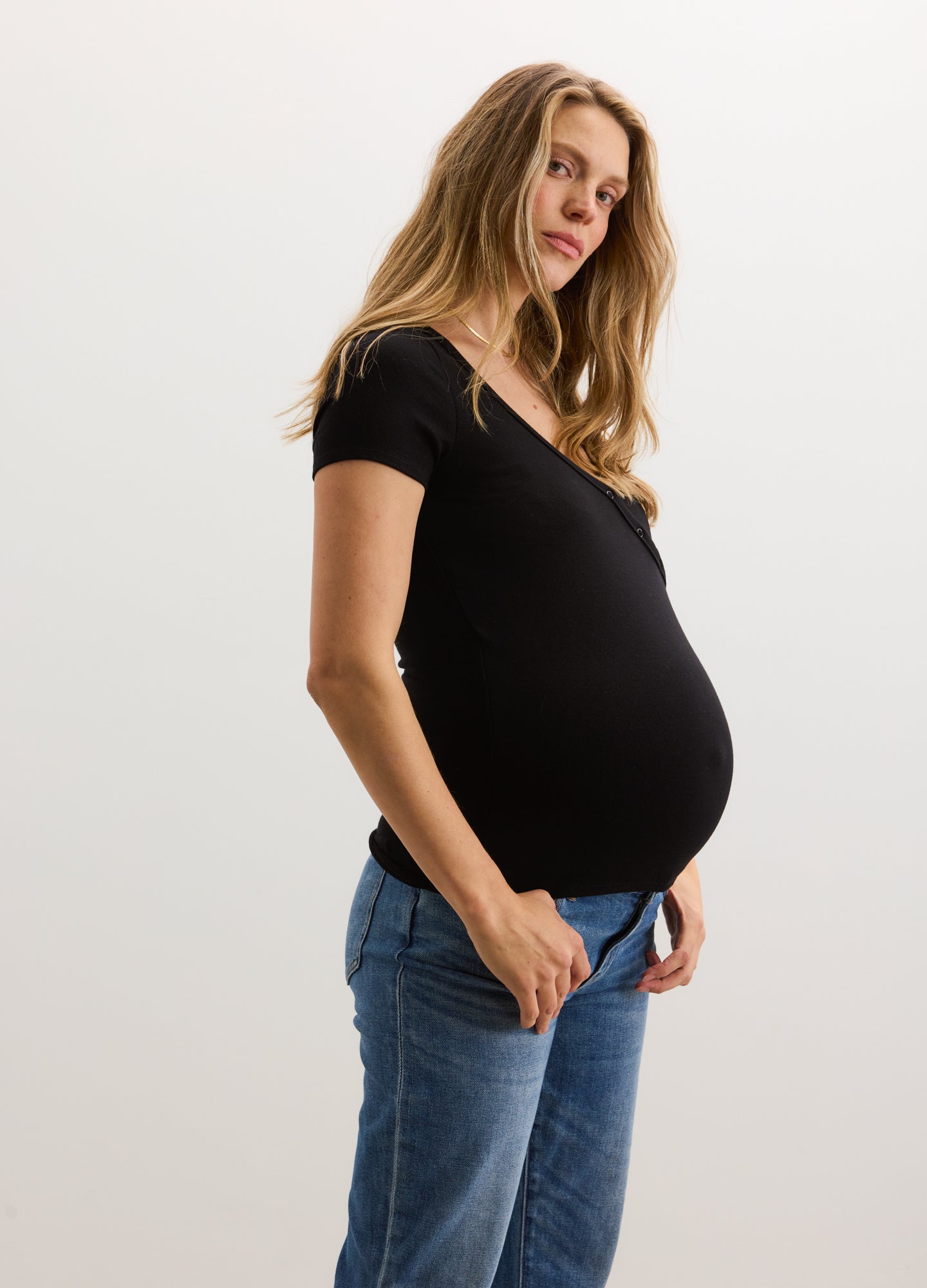 Black short-sleeve ribbed nursing tee with scoop neckline worn by pregnant woman.
