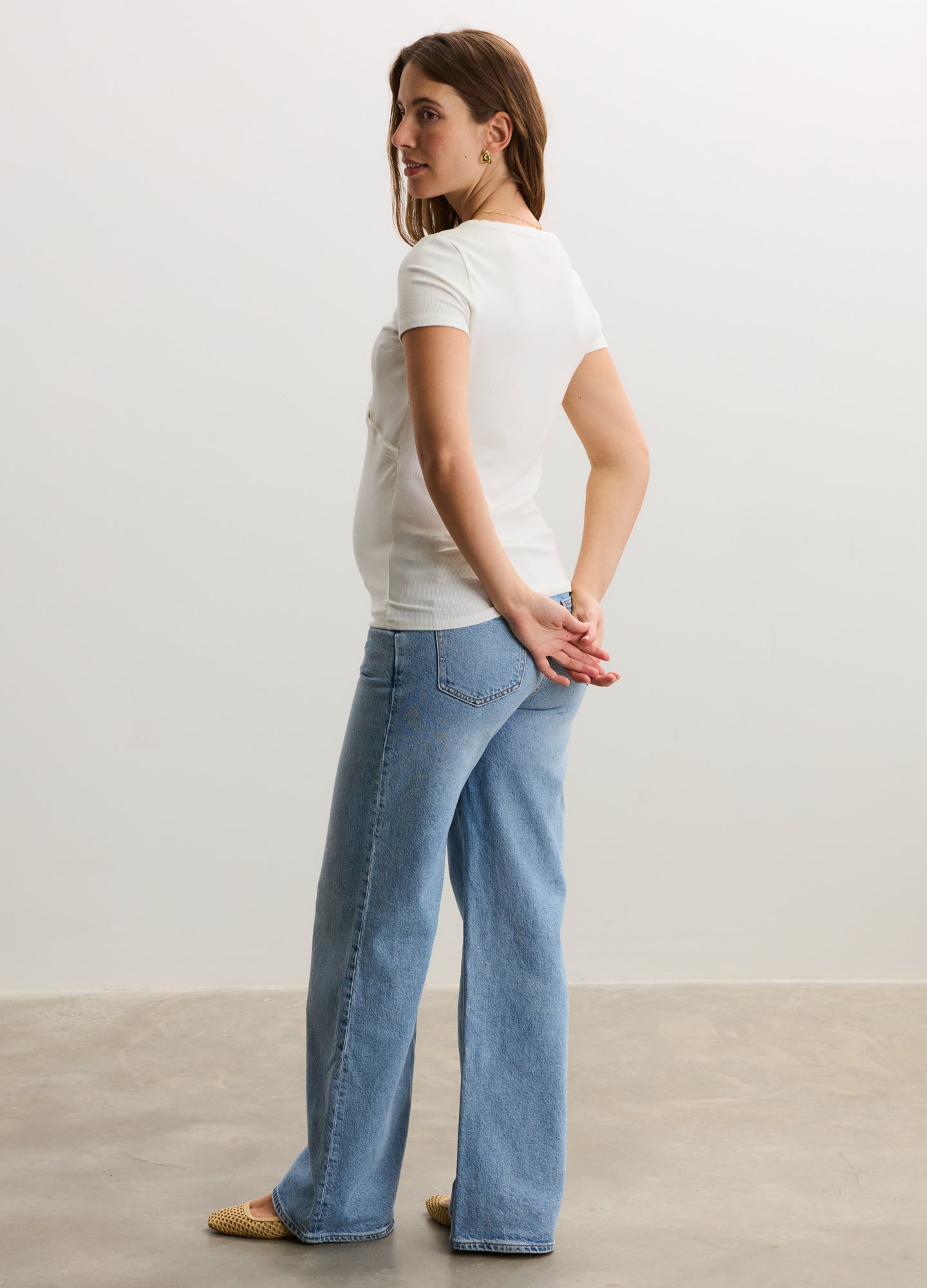 White ribbed short-sleeve nursing tee on a pregnant model paired with light blue maternity jeans.