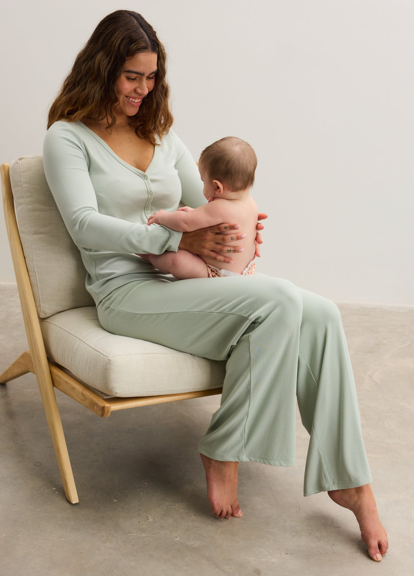 Light sage green ribbed maternity lounge pants with relaxed fit, worn by seated pregnant woman.