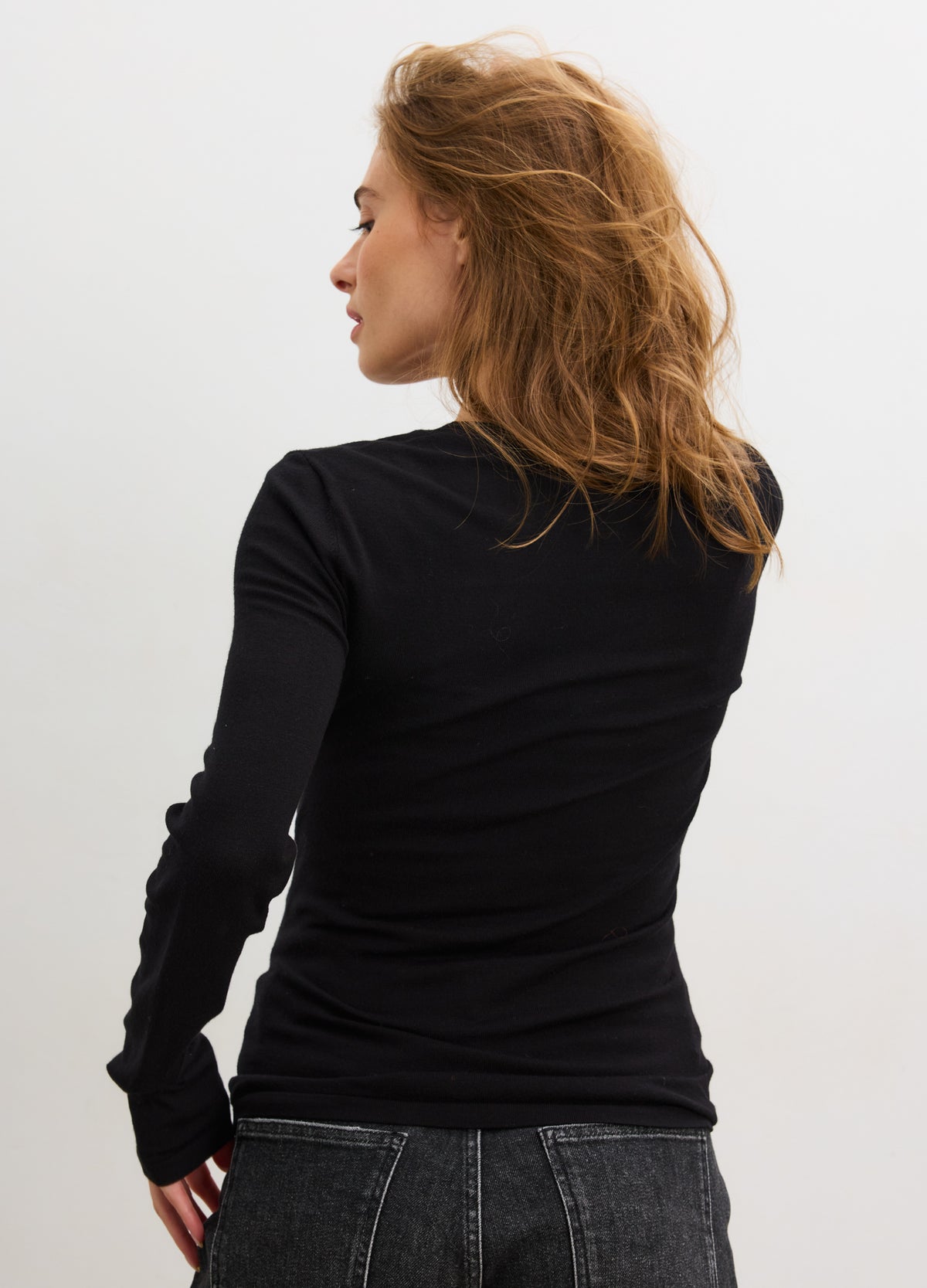 Black long-sleeve knit maternity tee with fitted silhouette on pregnant model, soft stretchy fabric.