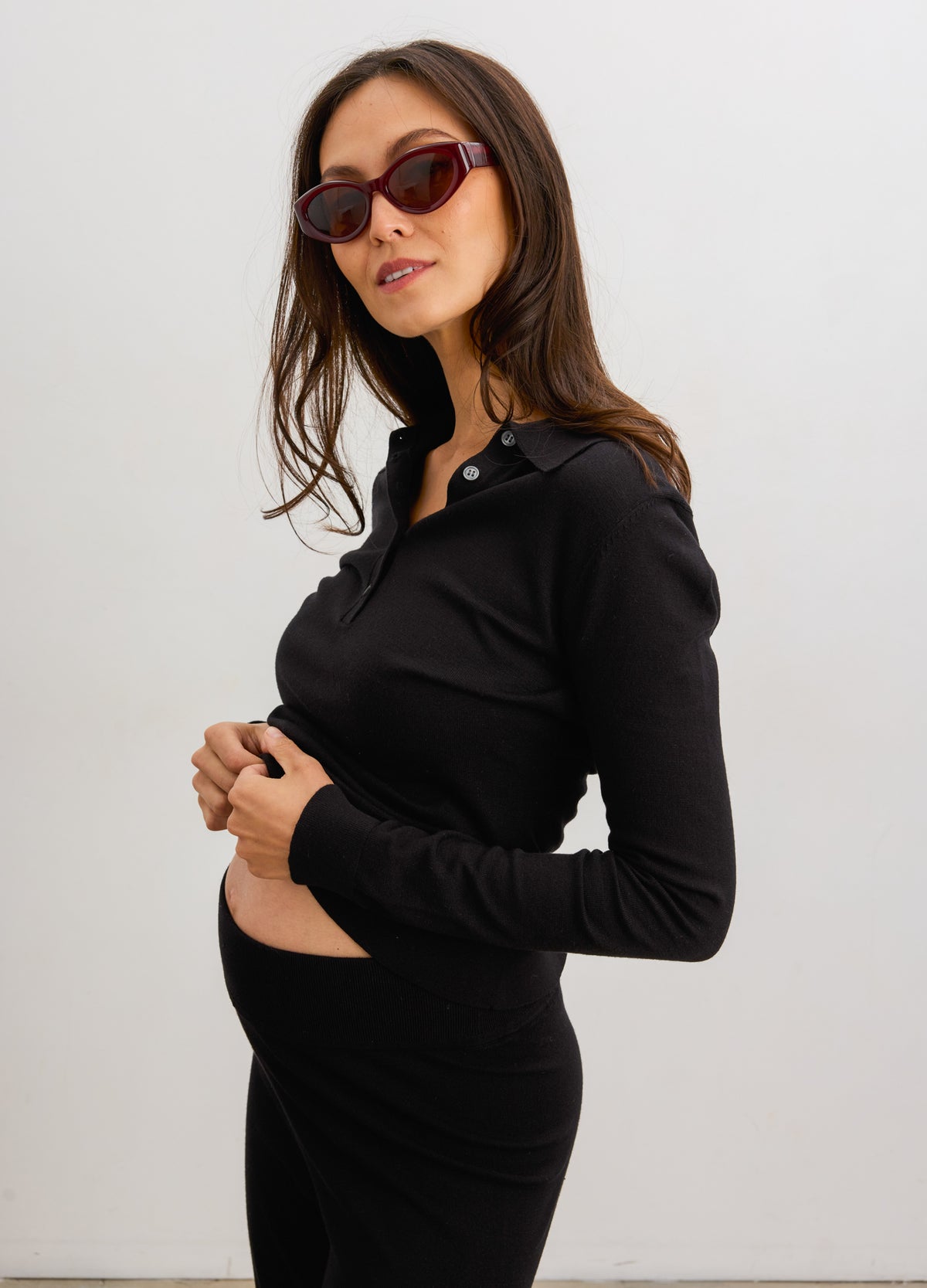 Black long-sleeve knit nursing polo with a buttoned collar on a pregnant model.