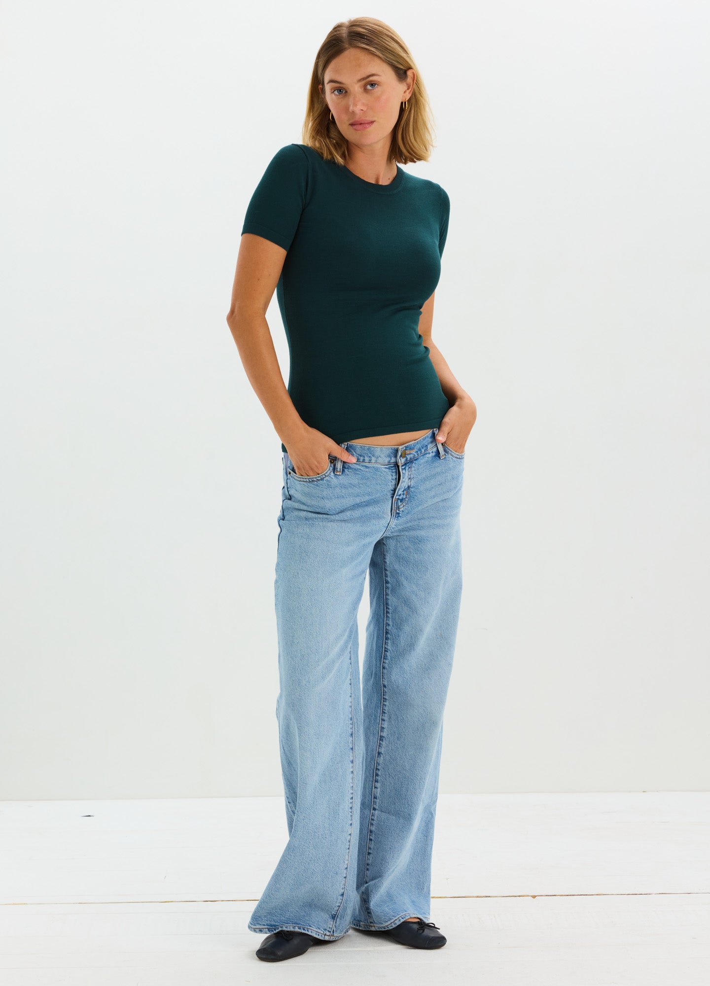 Dark green short-sleeve knit maternity tee with fitted silhouette worn by pregnant model paired with light blue wide-leg.