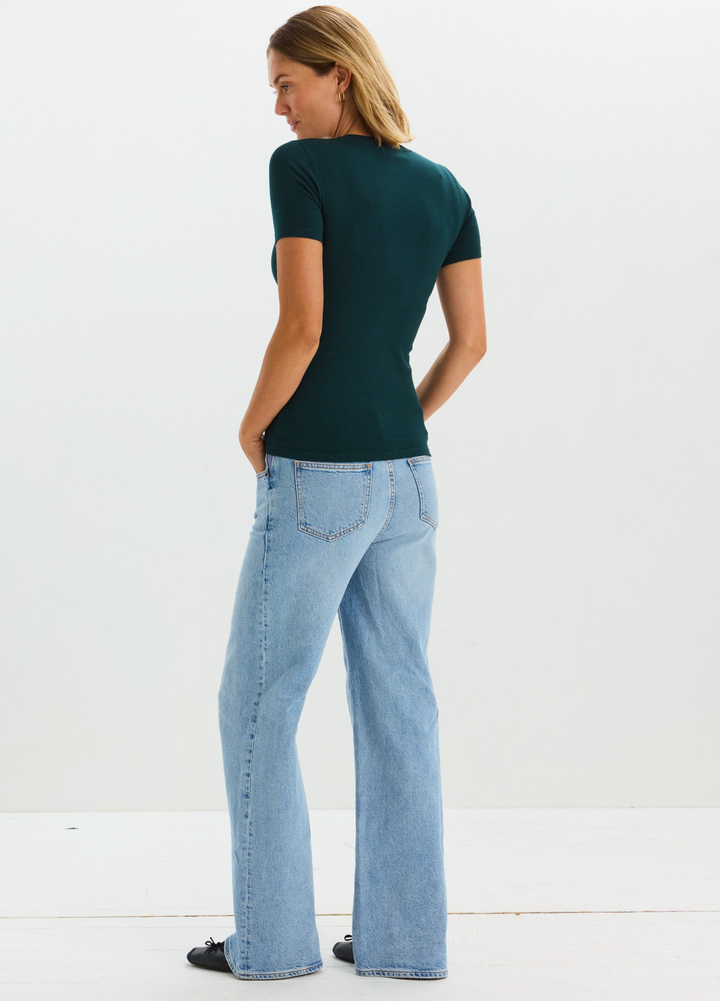Dark green short-sleeve knit maternity tee with fitted shape, worn with light blue high-waist jeans.