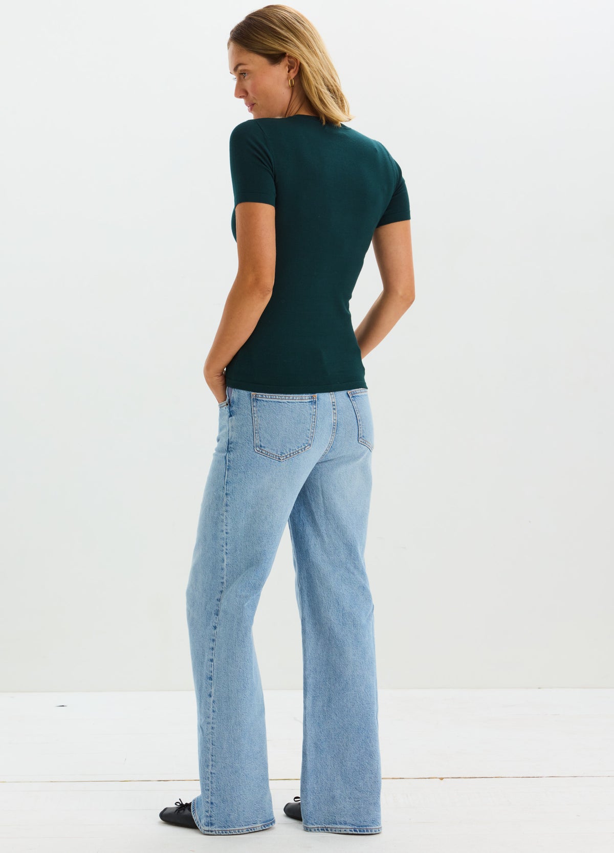 Dark green short-sleeve knit maternity tee with fitted shape, worn with light blue high-waist jeans.