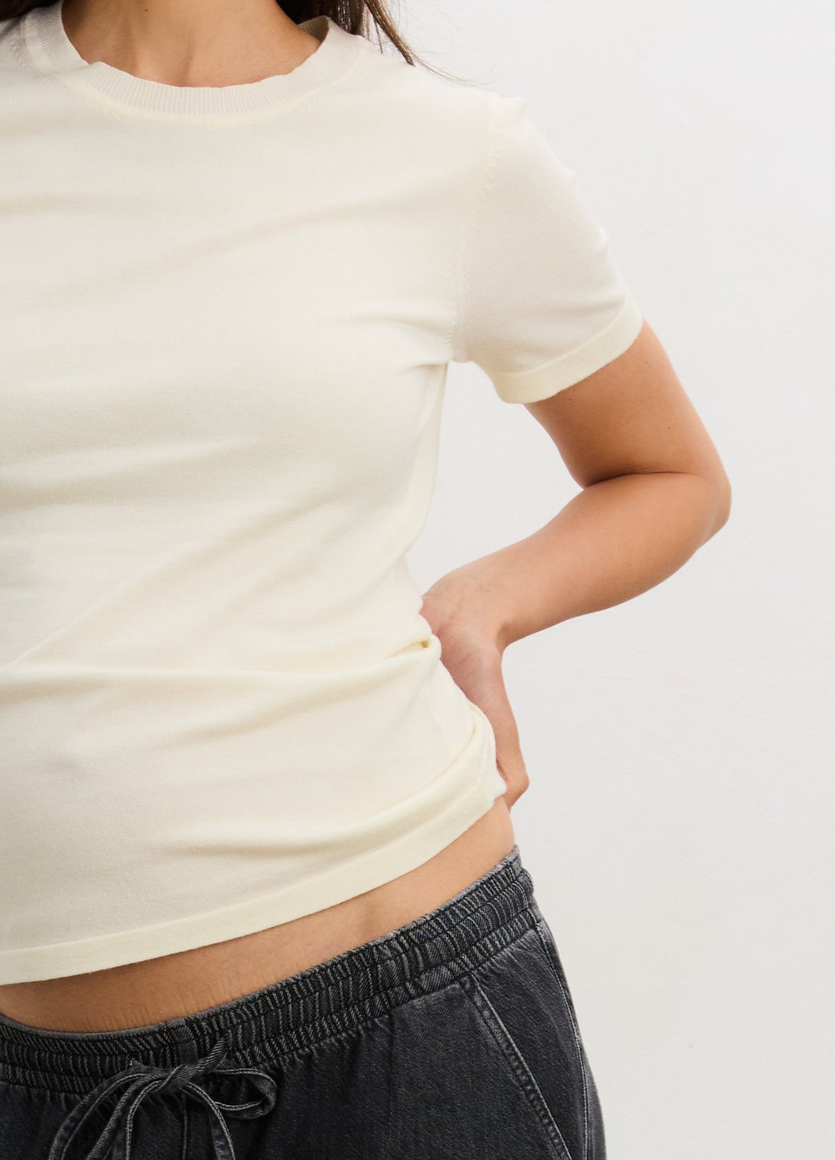 Cream-colored short-sleeve knit tee with a fitted shape designed for maternity wear.