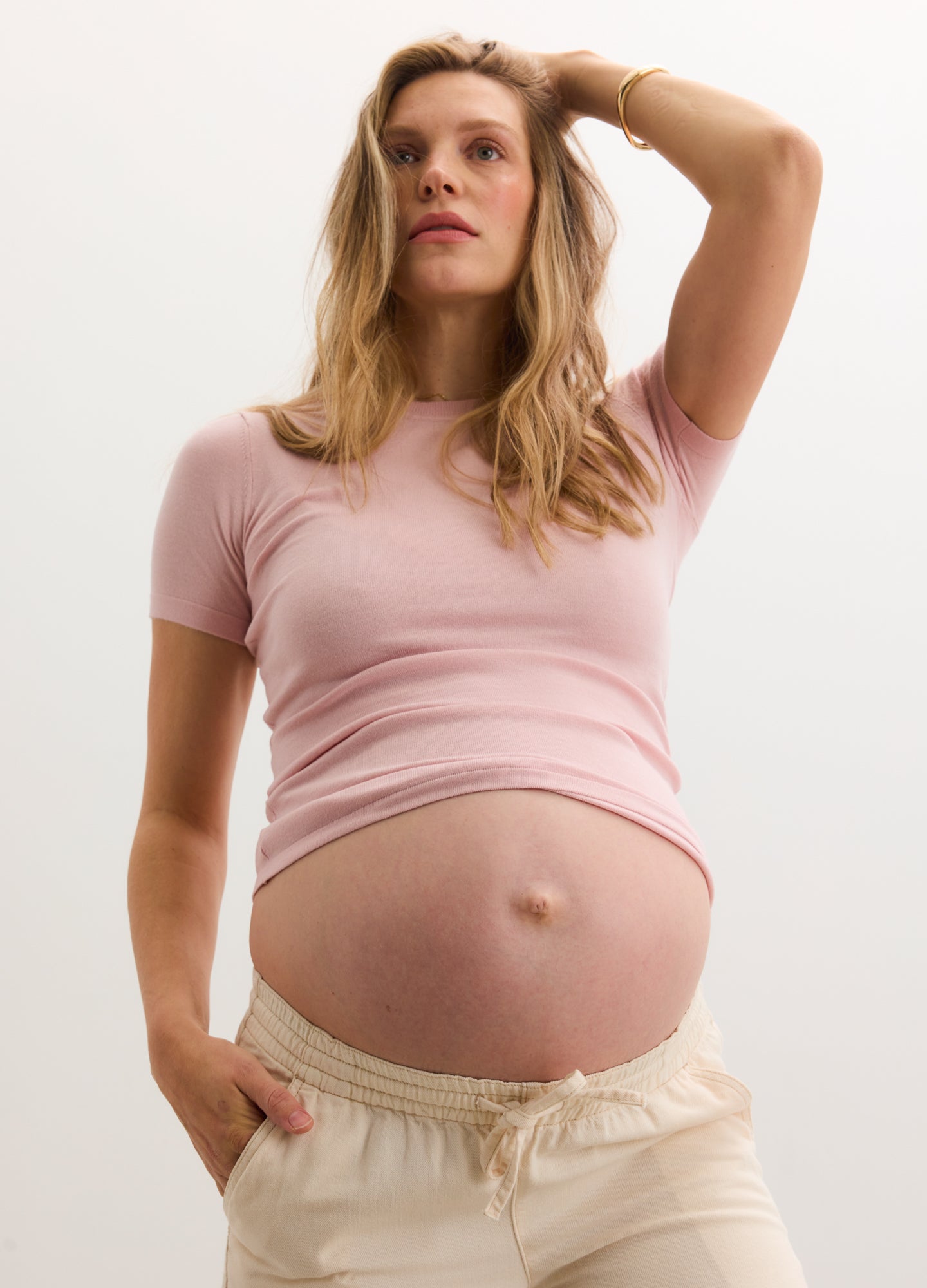 Light pink short-sleeve fitted knit tee styled for maternity with soft, stretchy fabric.