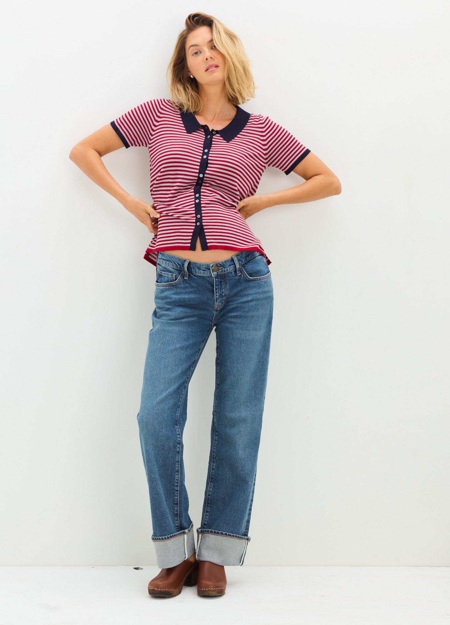 Pink and black short-sleeve maternity shirt with button front, paired with cuffed blue jeans and brown shoes.
