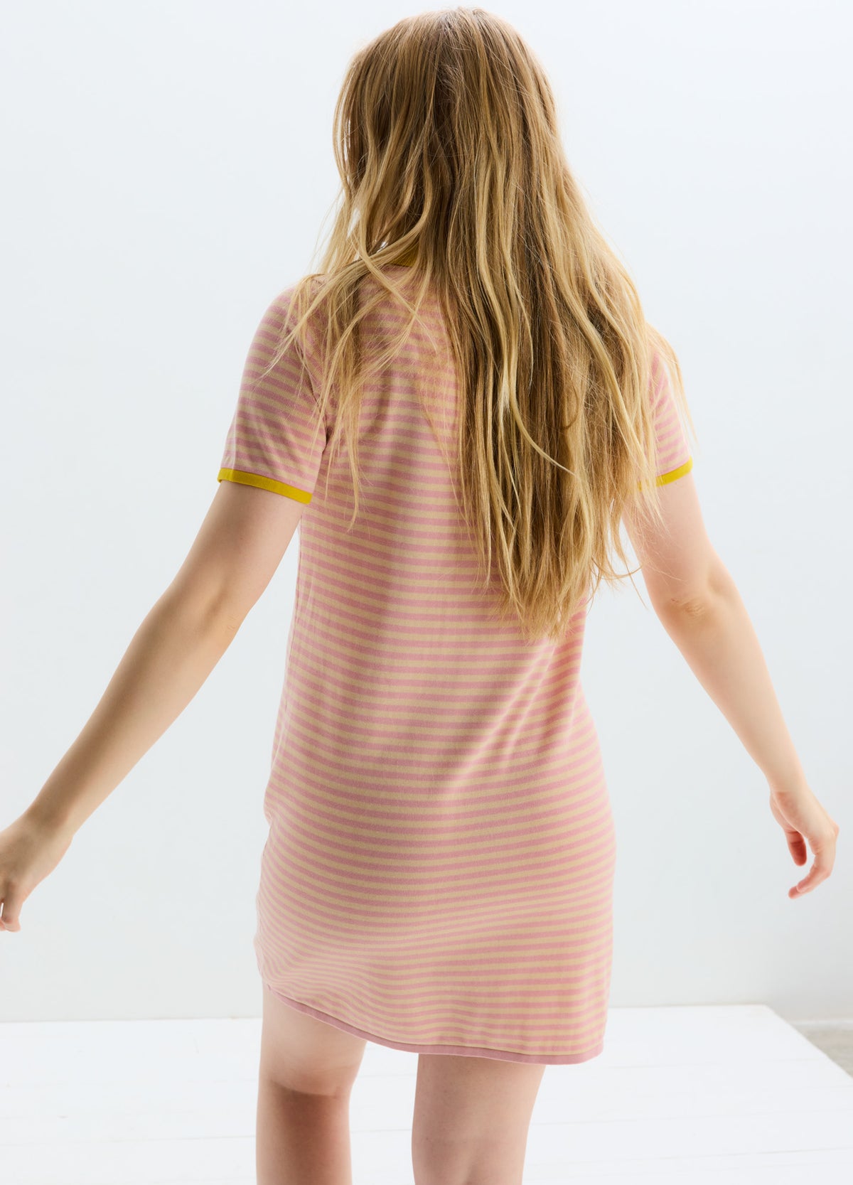 Soft pink and white striped maternity dress with short sleeves and yellow trim on sleeves and hem.