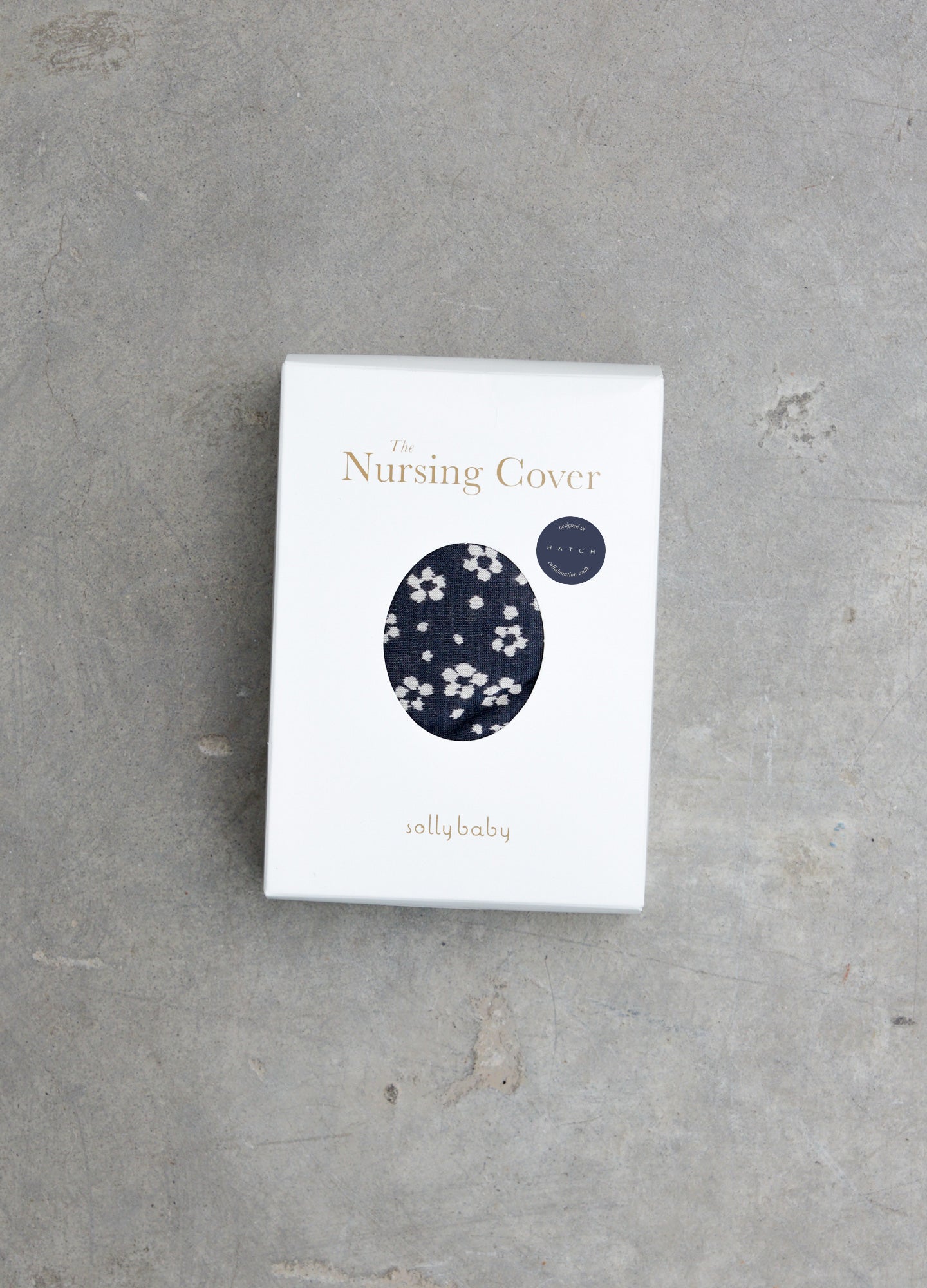 White rectangular box featuring a navy blue oval pattern with white flowers labeled Hatch X Solly Baby Nursing Cover.