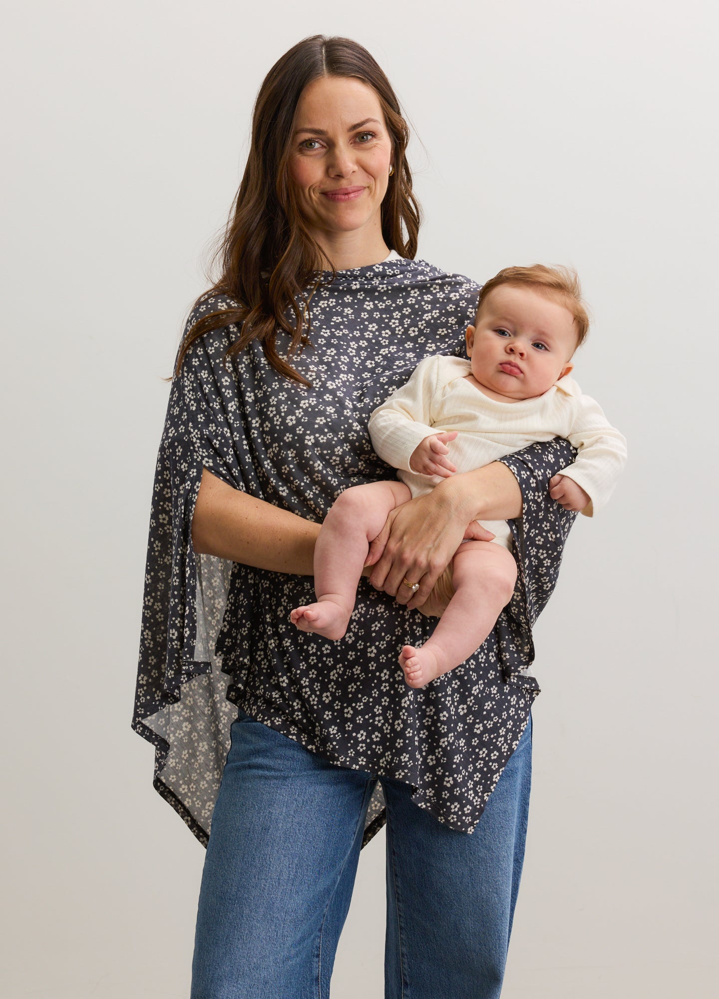 Soft black nursing cover with small white floral print worn over shoulders by woman holding baby.