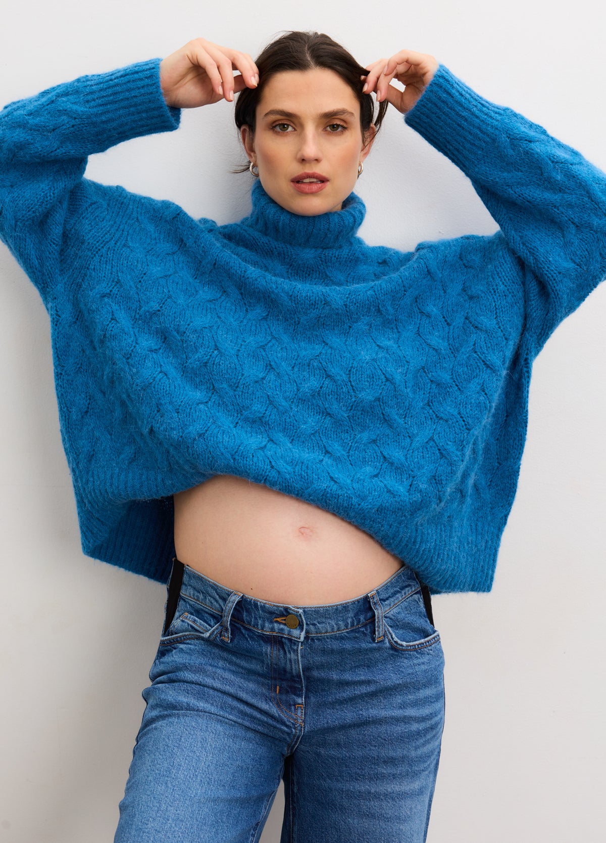 Bright blue alpaca cable knit turtleneck sweater styled for maternity with loose fit over pregnant belly.