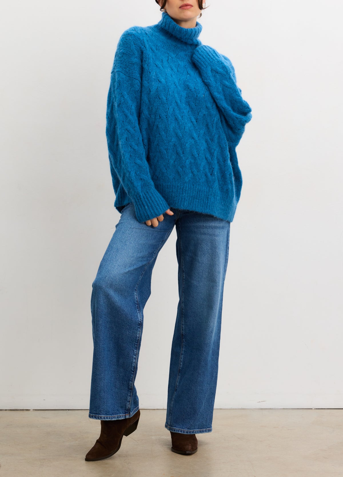 Teal blue alpaca cable-knit turtleneck sweater with relaxed fit and long sleeves.
