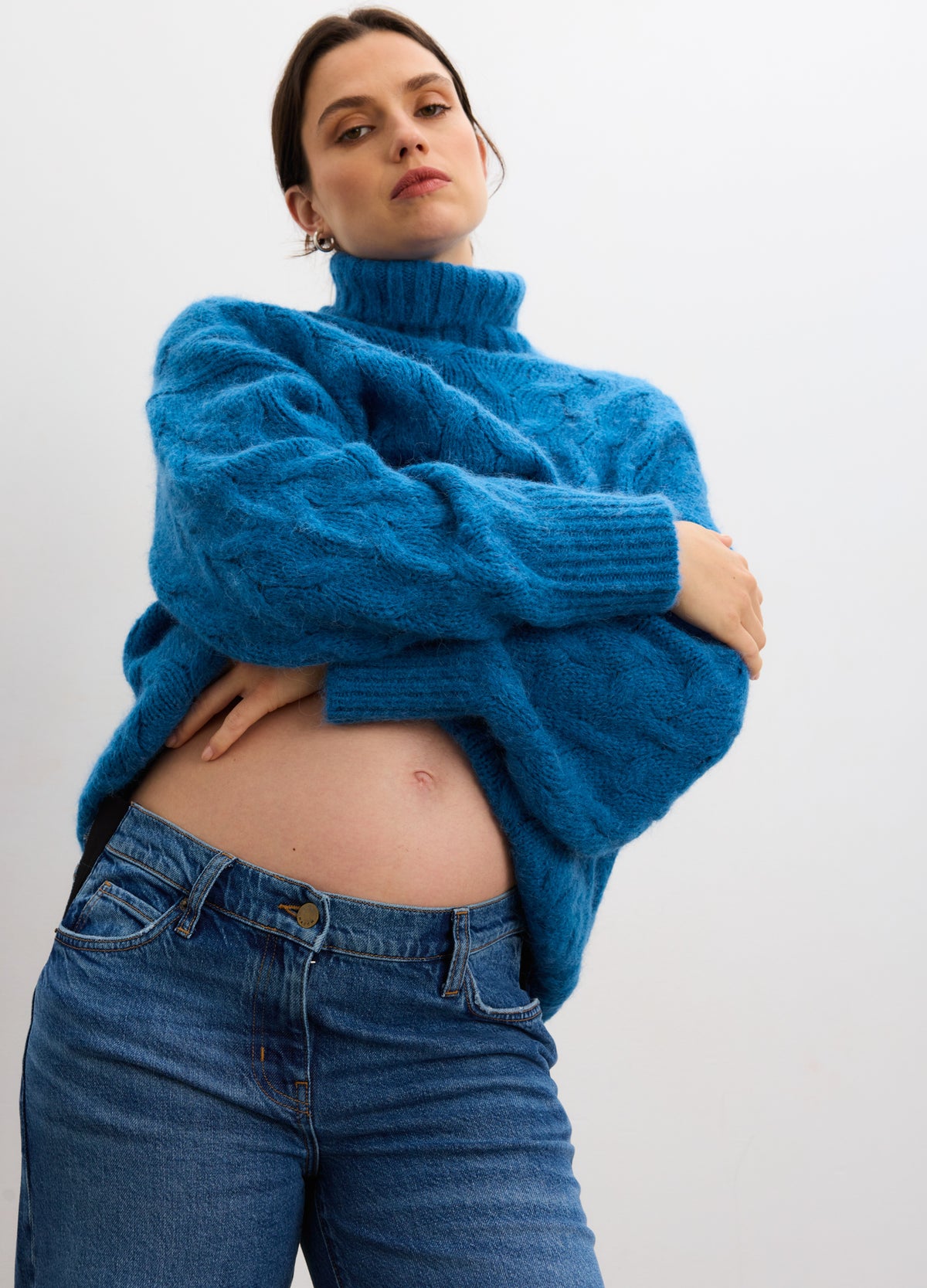 Blue alpaca cable-knit turtleneck sweater with long sleeves and relaxed fit worn over jeans.