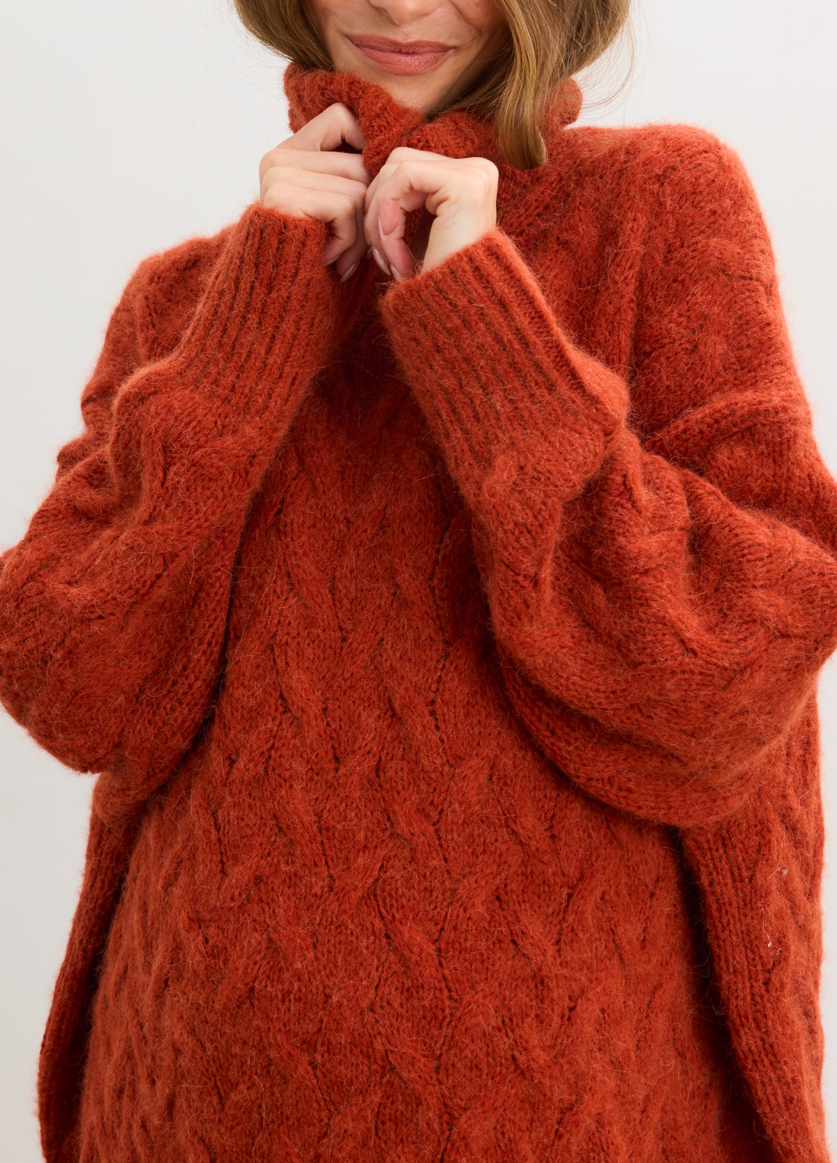 Rust-colored alpaca cable-knit turtleneck sweater with cozy, oversized sleeves designed for maternity wear.