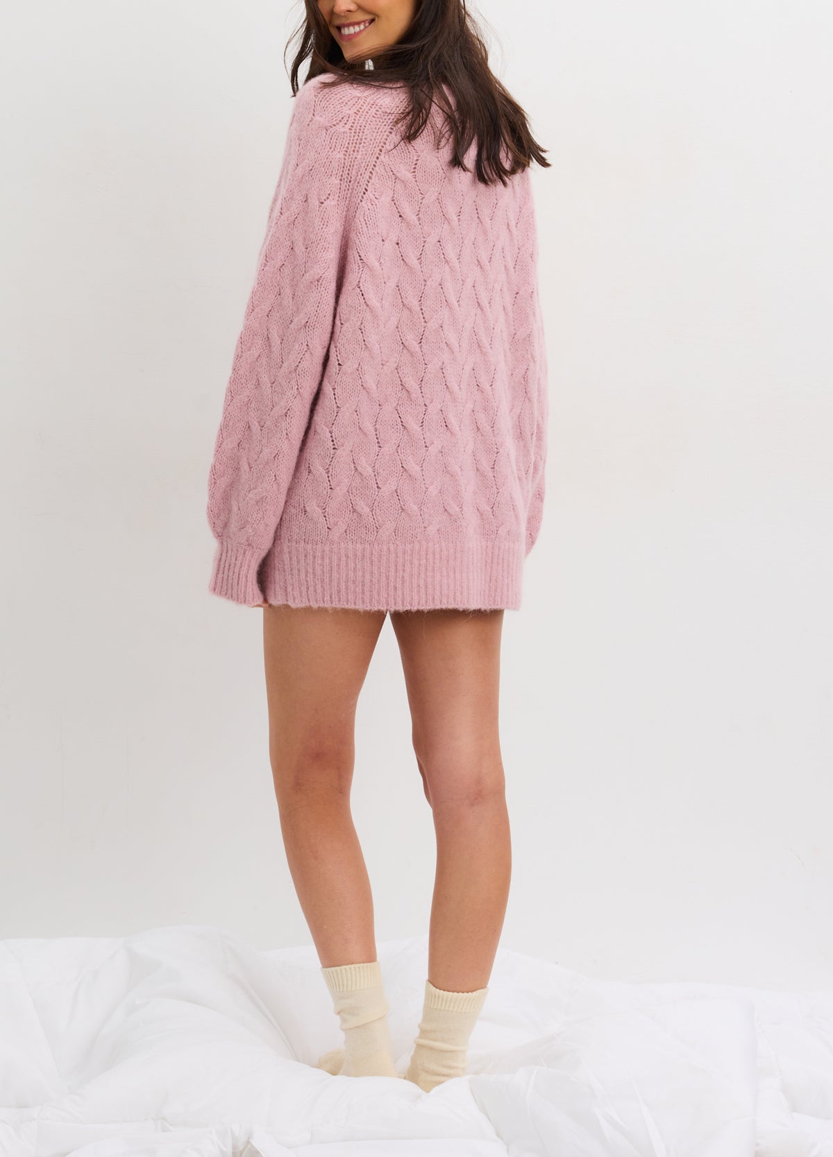 Soft pink alpaca cable-knit cardigan with long sleeves and relaxed fit, styled for maternity wear.