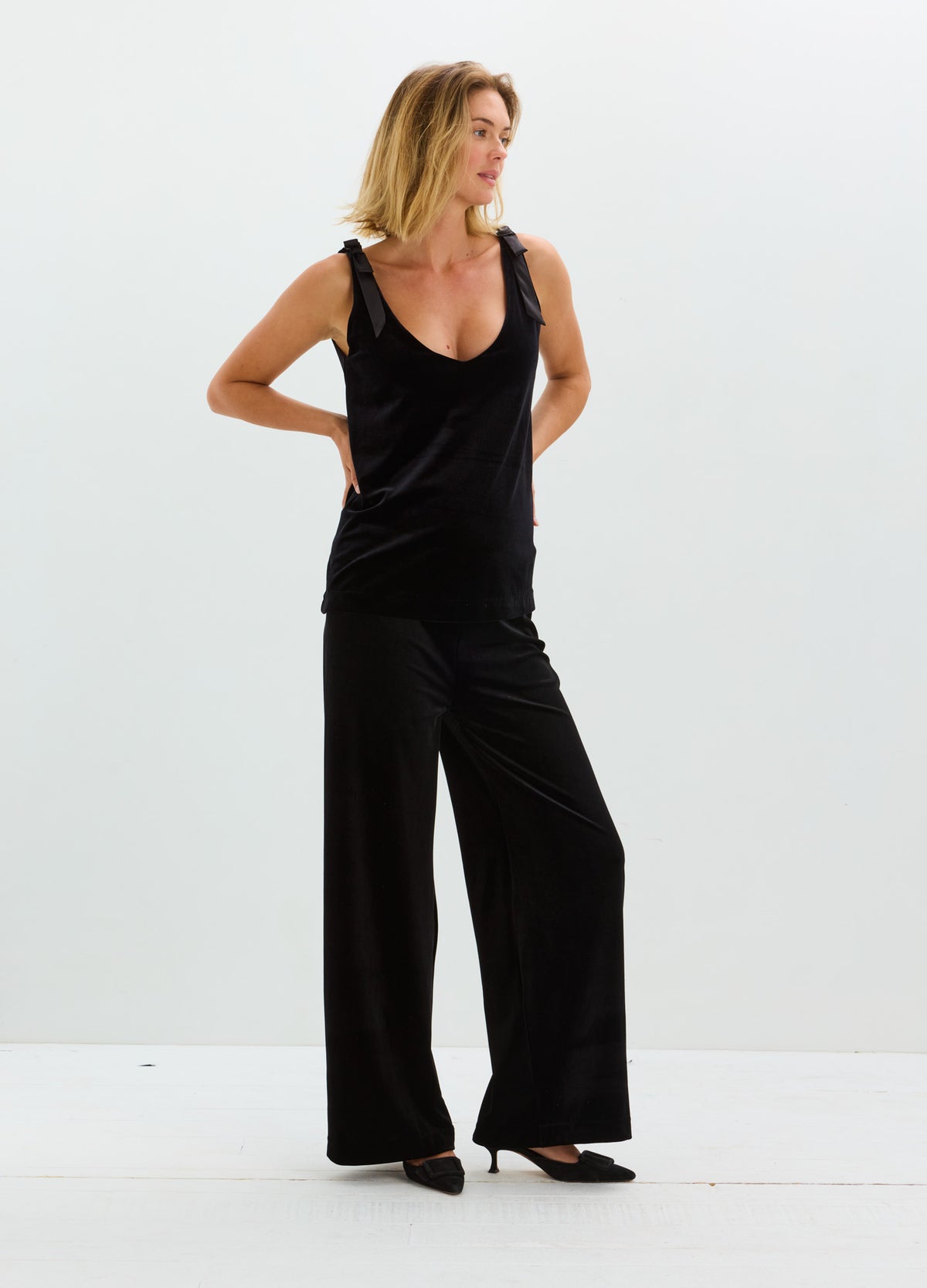 Black sleeveless velvet top paired with wide-leg black velvet pants and pointed heels.