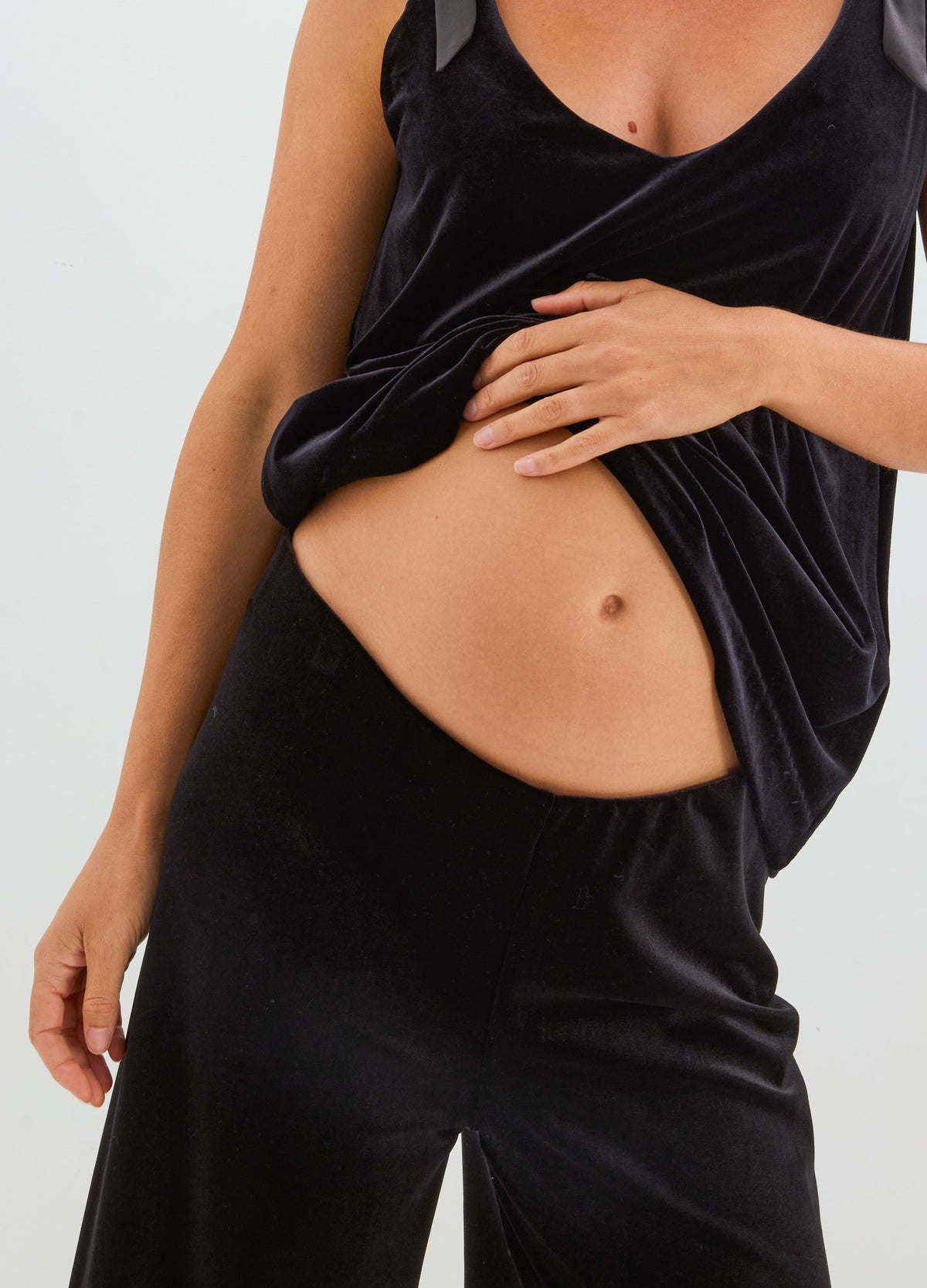 Black stretch velvet pants with a sleek, fitted silhouette and soft sheen, styled with a matching sleeveless top.