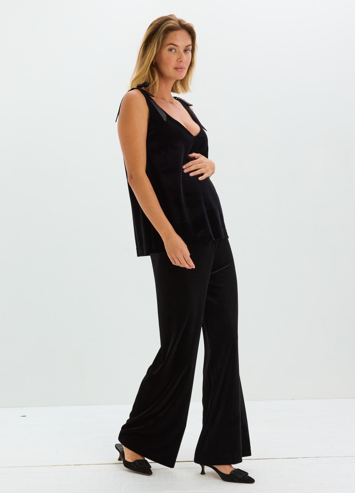 Black stretch velvet sleeveless top with a V-neckline, paired with wide-leg trousers.