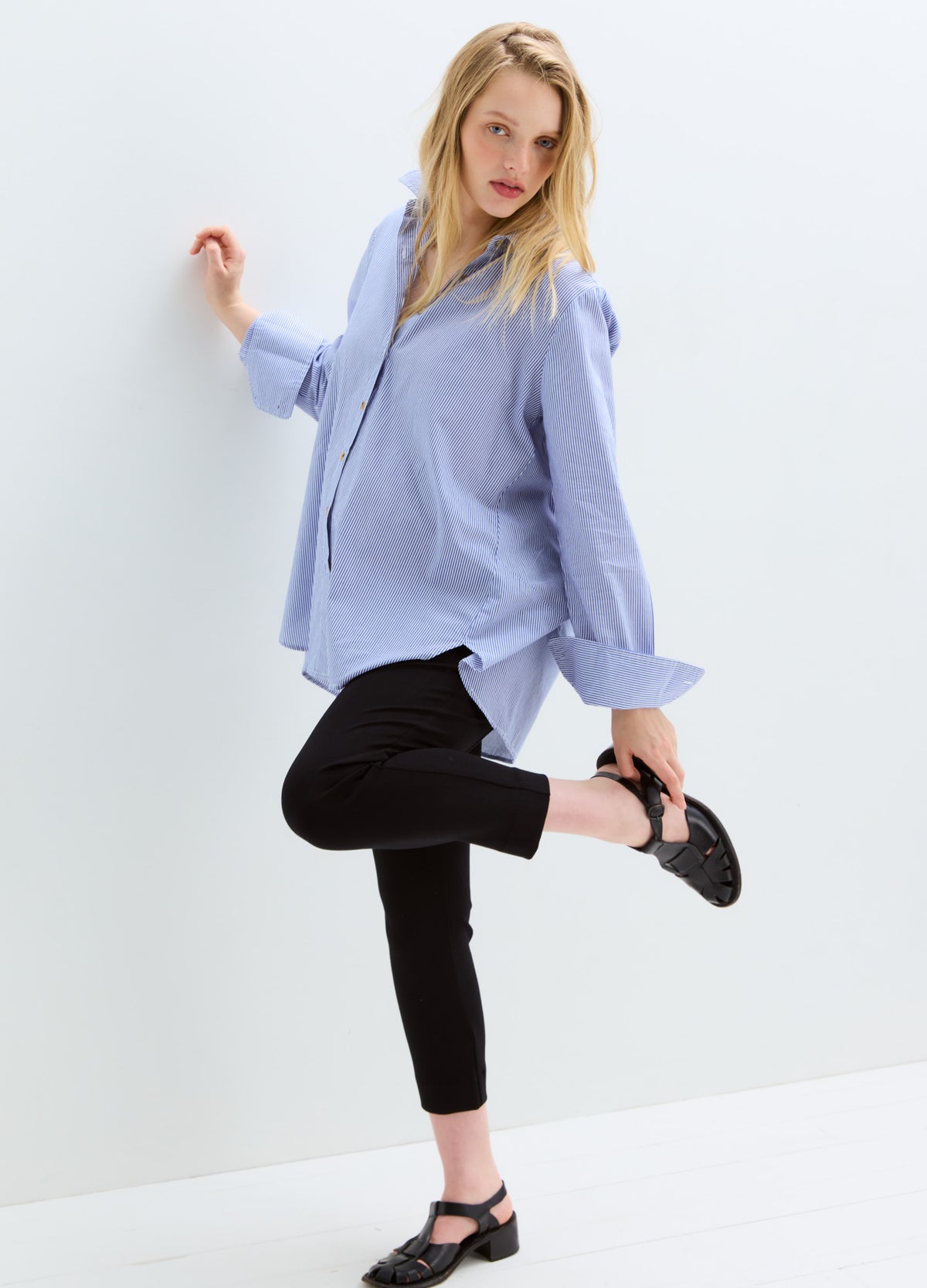 Light blue long-sleeve maternity buttondown shirt with classic collar paired with black cropped pants and black flats.