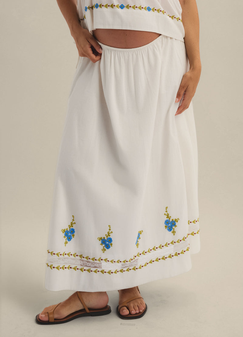 White maternity skirt with elastic waistband, floral embroidery hem, and relaxed fit.