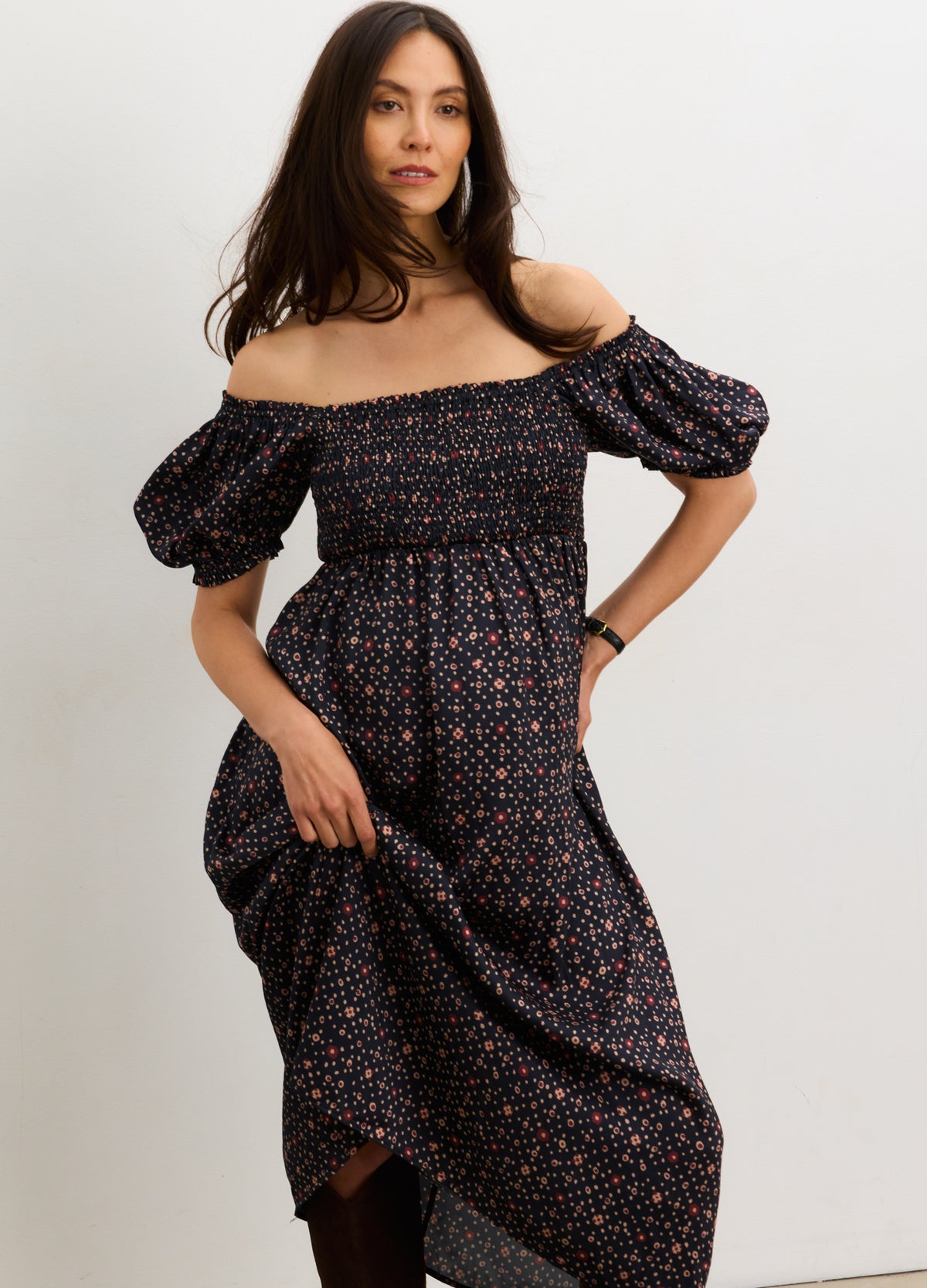 Navy maternity dress with smocked bodice, puff sleeves, and small floral print, worn by pregnant model.