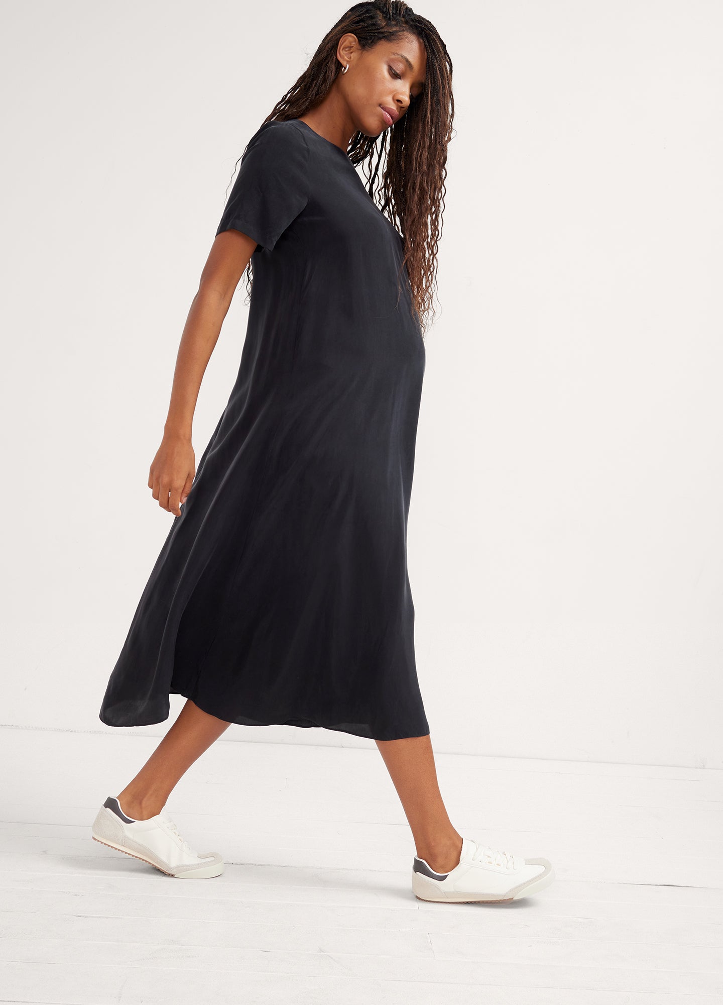 Black maternity midi dress with short sleeves and relaxed fit, worn with white slip-on shoes.