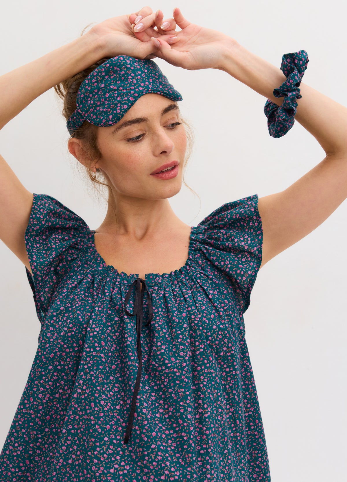 Pregnant woman wearing maternity nightdress with blue floral print and matching eye mask and scrunchie.