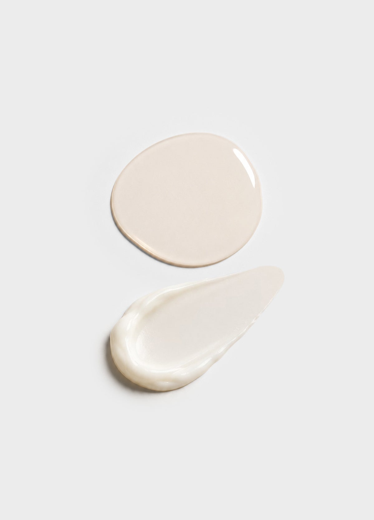 Two beige and white cream swatches with smooth, glossy textures on a white background.