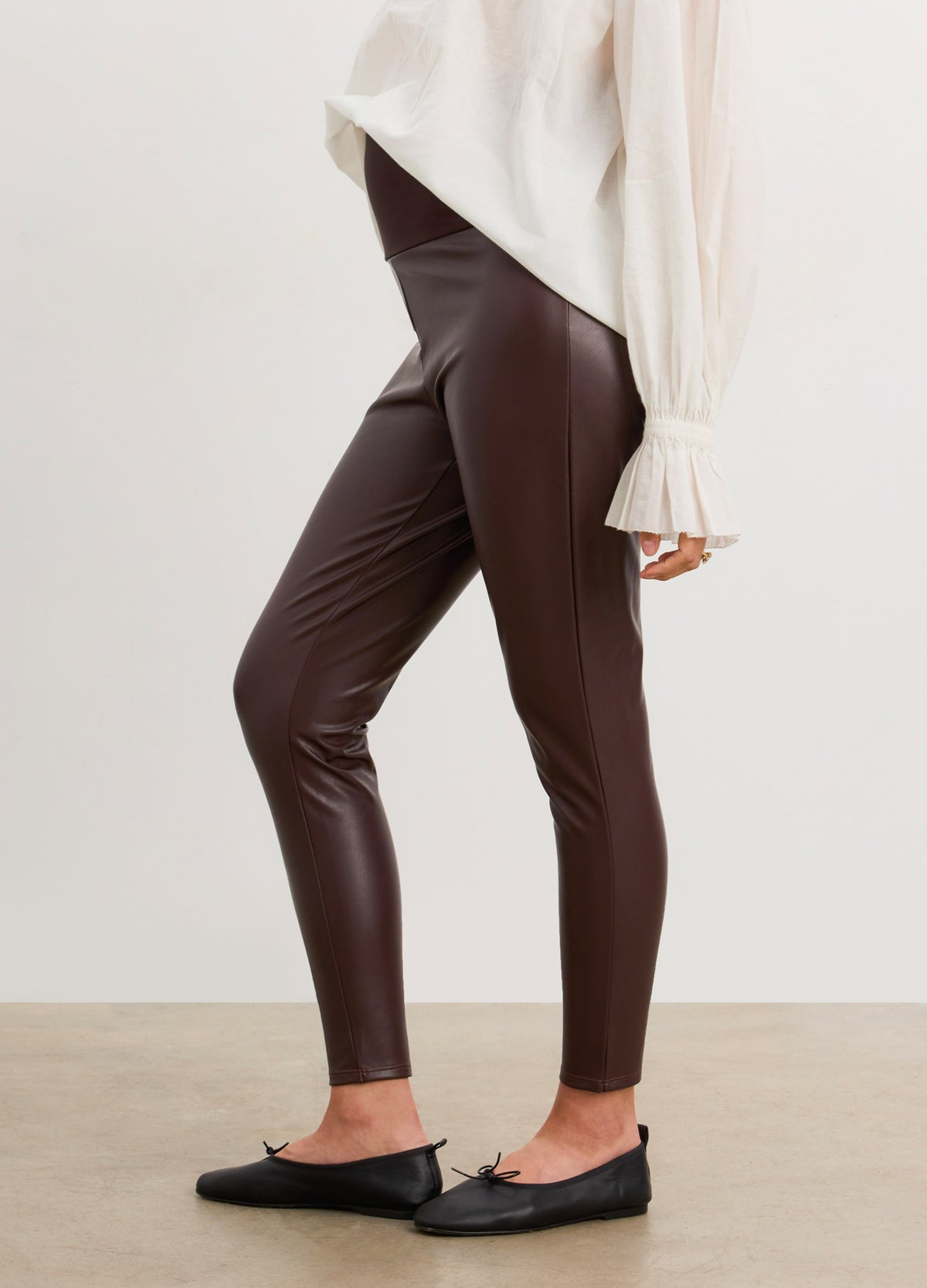Dark brown vegan stretch leather maternity leggings with a smooth, fitted silhouette and a high, supportive waistband.