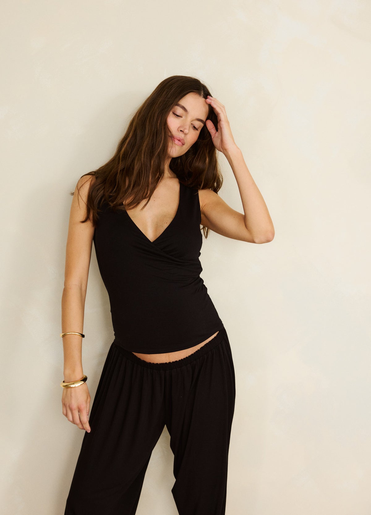 Black short-sleeve maternity nursing wrap top with V-neck worn by pregnant woman.